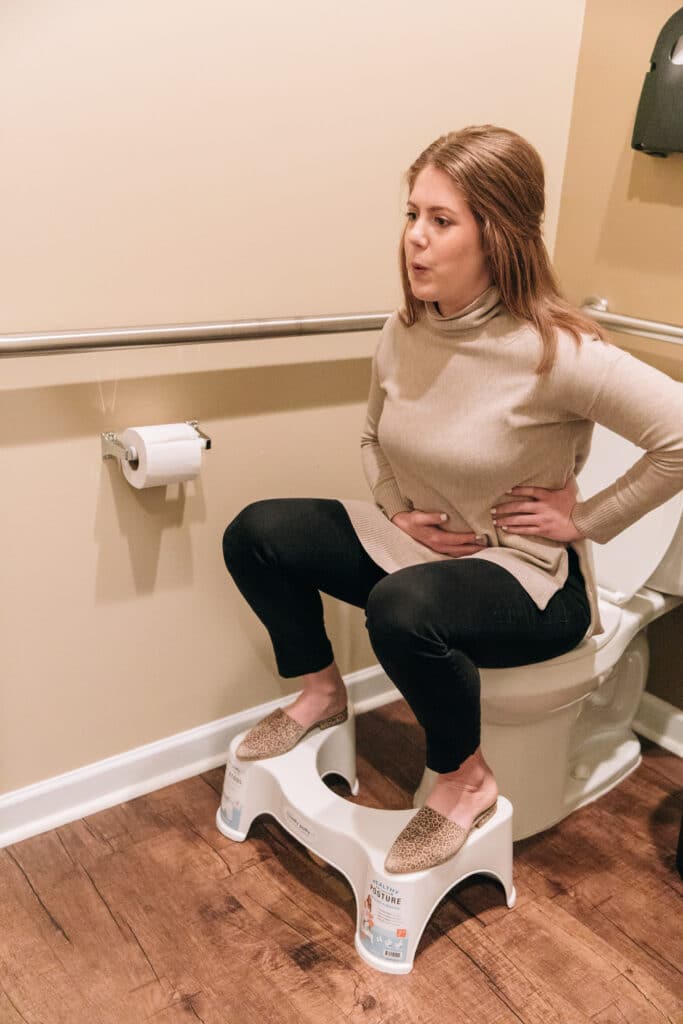 female sitting on toilet in bathroom