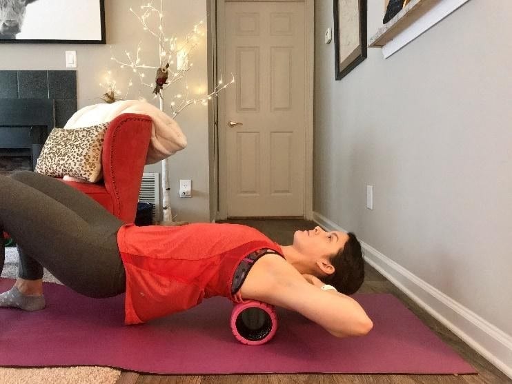 Female performing foam rolling of her spine to improve mobility