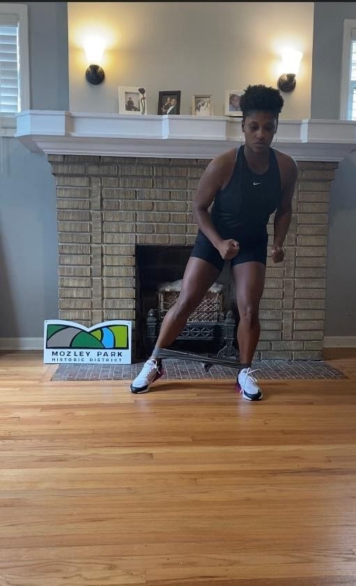 Female standing performing hip strengthening exercise 