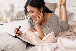 female lying in bed journaling